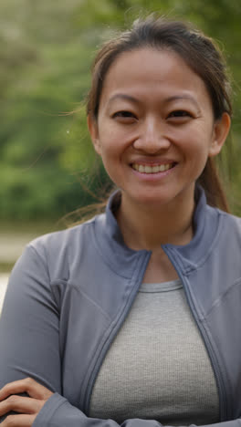 Vertical-Video-Portrait-Of-Smiling-Mid-Adult-Woman-Exercising-Doing-Work-Out-Outdoors-In-Forest-Wearing-Sports-Clothing-Shot-In-Real-Time